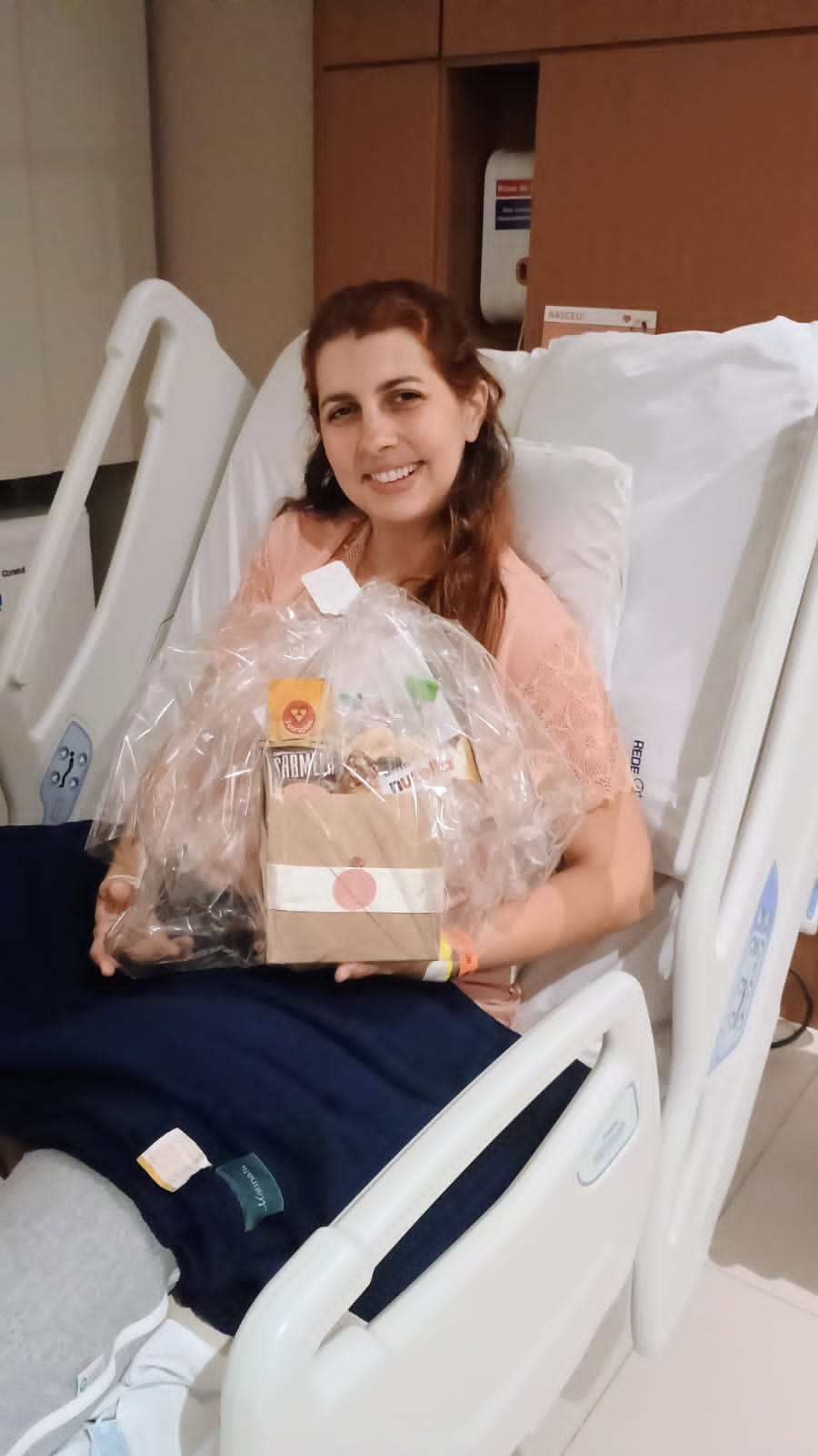 Mãe de um recém-nascido sorrindo com a cesta enviada por uma amiga